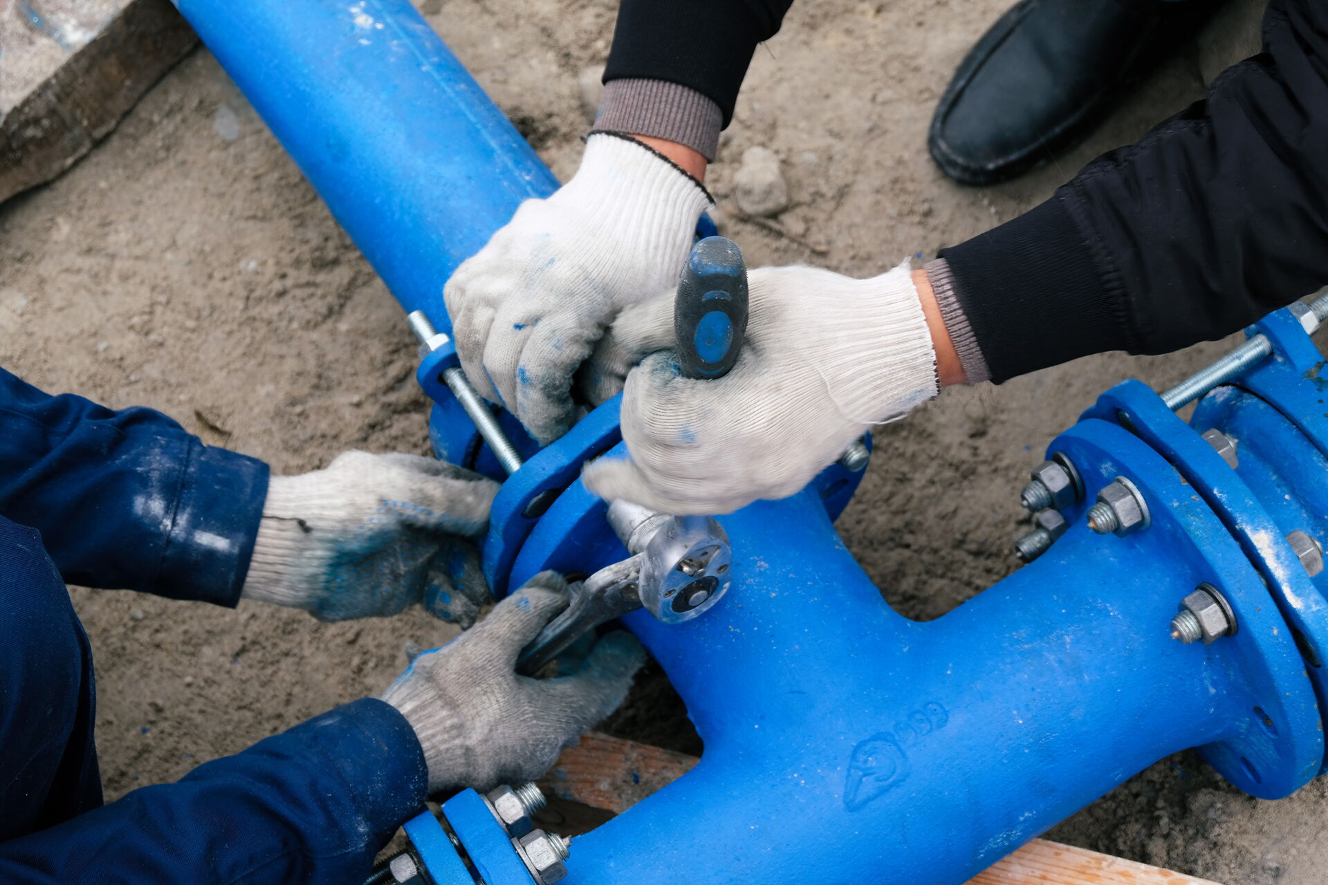 Große blaue Wasserarmatur & Hände von zwei Servicetechniker die gerade Feststellschrauben festziehen
