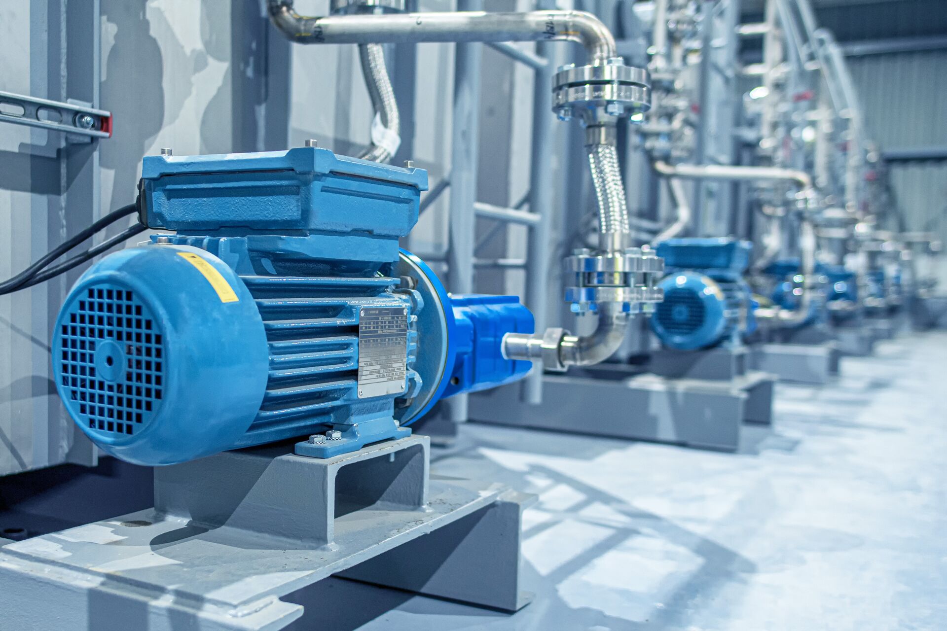 Blaue Elektromotoren treiben Pumpen in einer Industrieanlage an